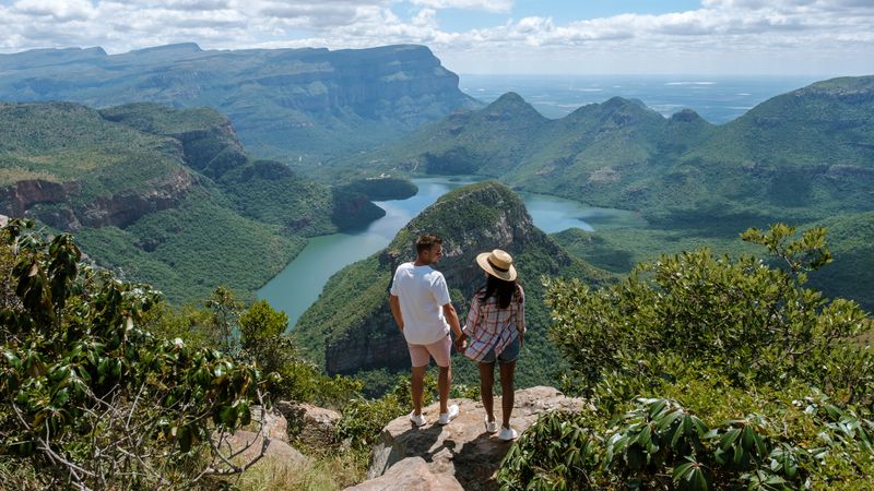 Couple enjoys breathtaking views at Blyde River Canyon on the Panorama Route in South Africa, surrounded by lush greenery and dramatic landscapes, capturing the beauty of this tourist destination.