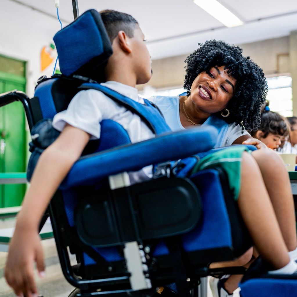 A caregiver warmly interacts with a child in a wheelchair.
