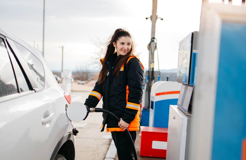 Woman refueling a car at a gas station and smiling