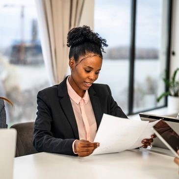 Businesswoman reviewing documents in a modern office with large windows.