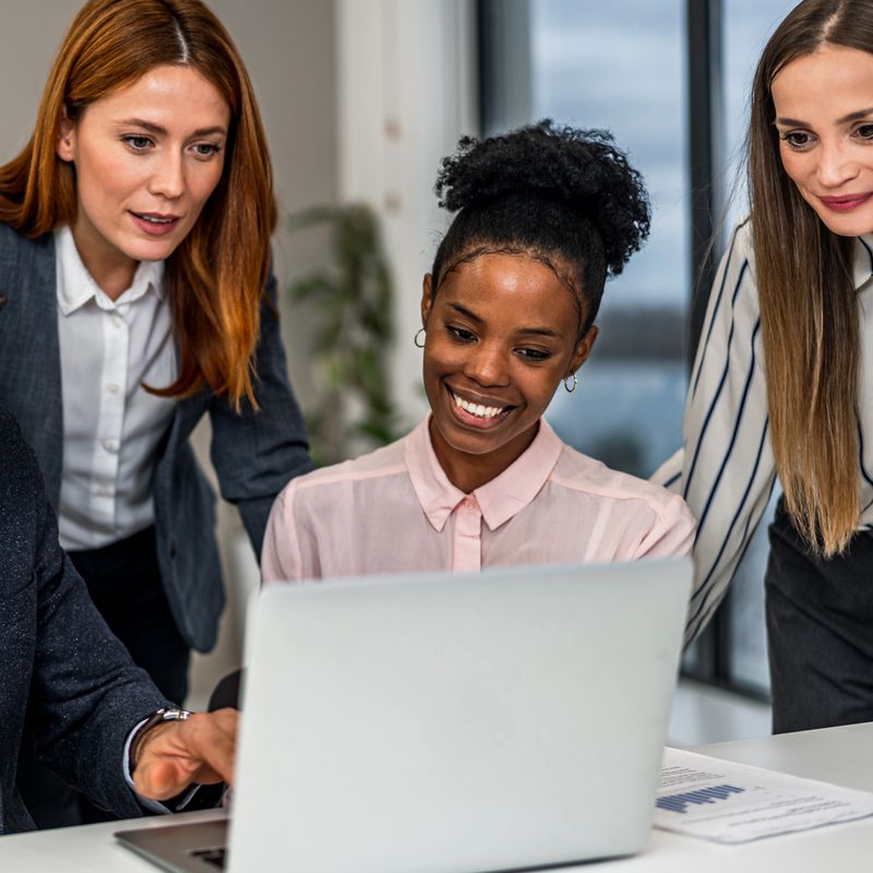 Multi-ethnic businesspeople working together, looking at laptop screen and discussing project. Teamwork and success concept