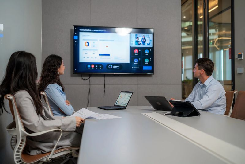 Diverse business team discussing and sharing ideas for a new strategy in a meeting room. Group of professionals analyzing marketing data on laptops and a large monitor during a collaborative workshop in a modern office.