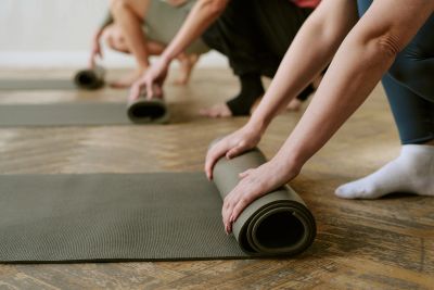 People rolling up yoga mats indoors.