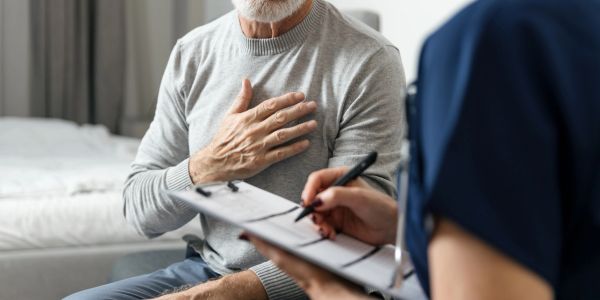 Older man holding chest during medical consultation.