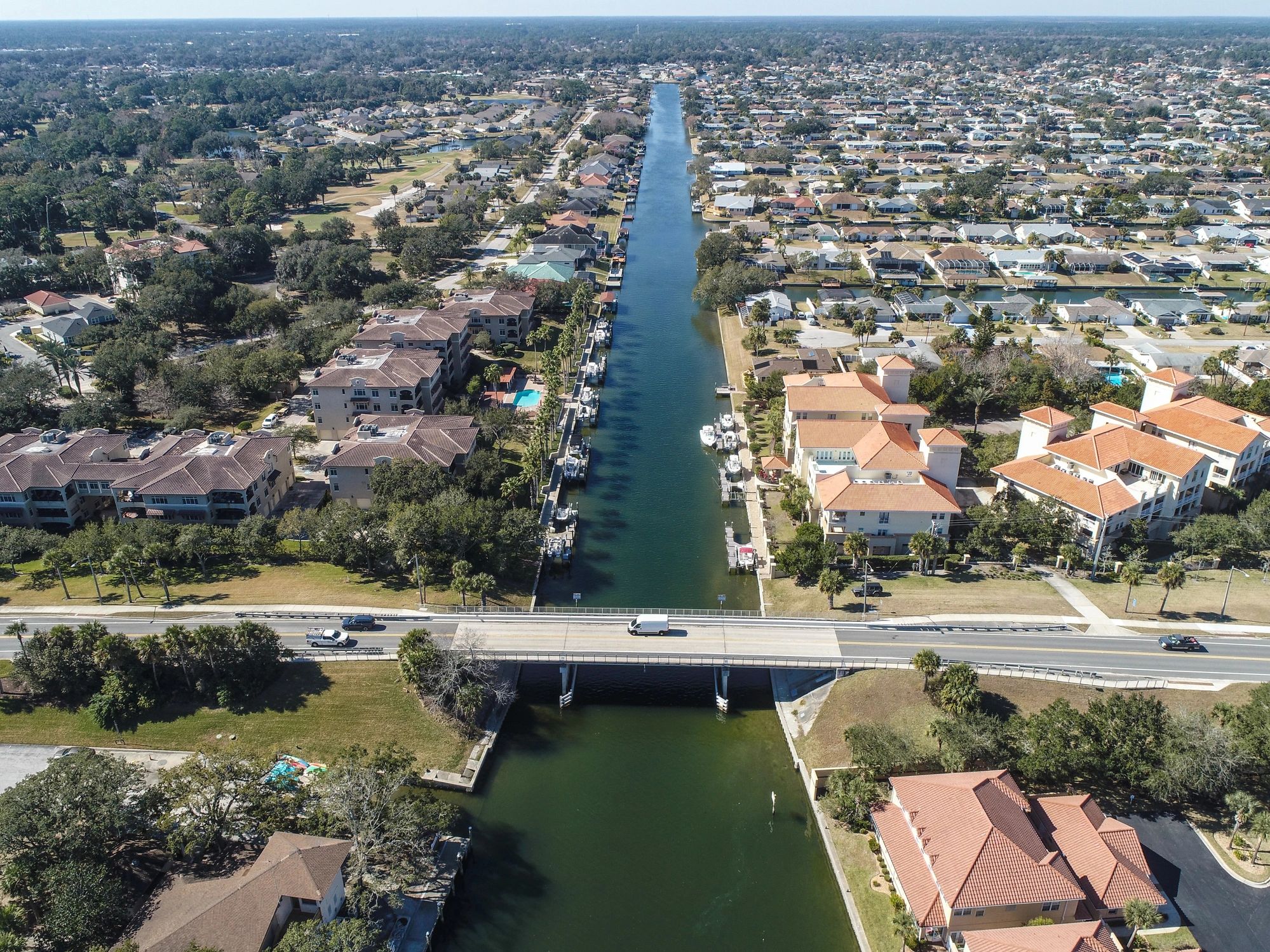 Aerial view of a canal running through a residential area with a bridge.