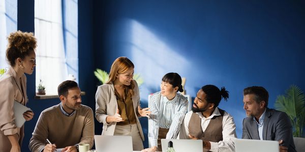 A diverse group collaborating in a modern office with laptops and sunlight.