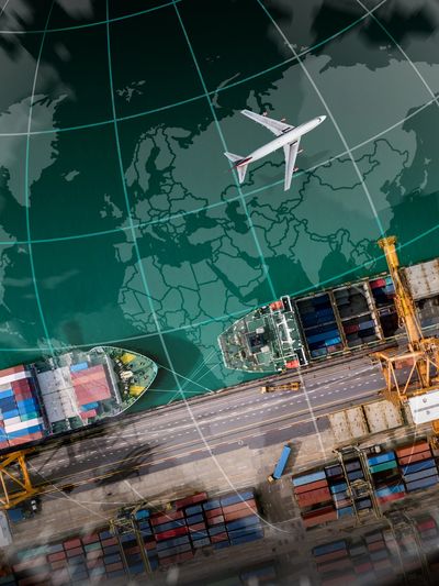 Aerial view of cargo ships and airplane over a map.