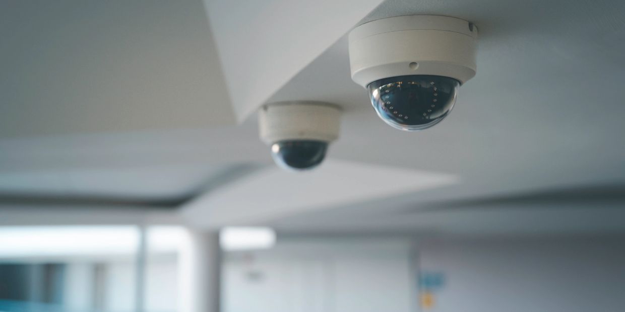 Two dome security cameras mounted on a ceiling indoors.