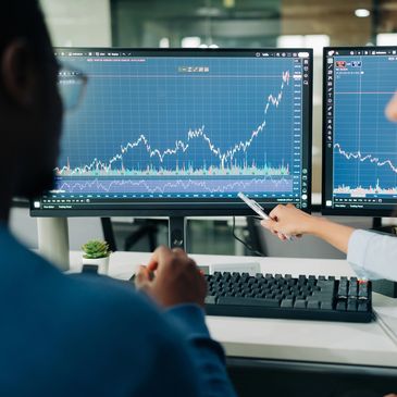 Two people analyzing stock market trends on computer screens.