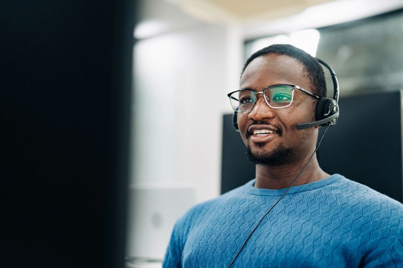 Smiling customer service representative at computer in modern office