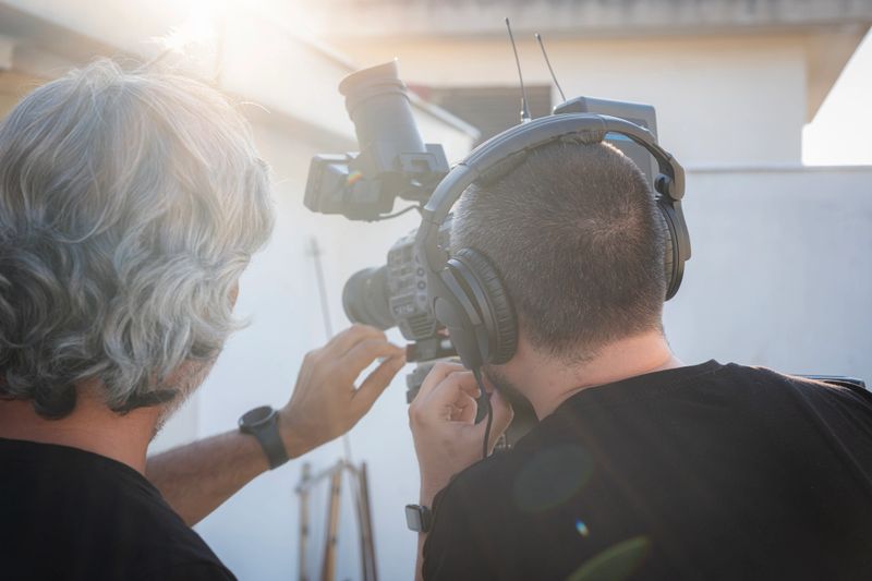 Video production crew collaborating on a film set, recording content with professional camera equipment and wearing headphones, ensuring high-quality audio and visuals for a new media project