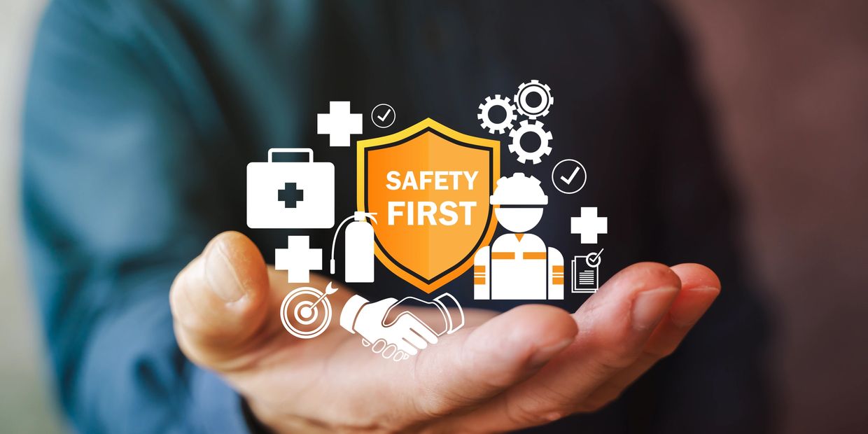 Hand holding safety icons with a 'Safety First' shield symbol.