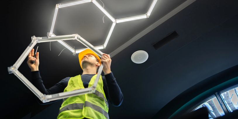 Electrician installing hexagon-shaped ceiling lights.