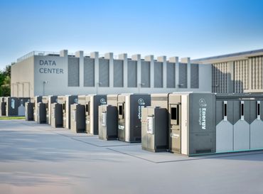 Modern data center with energy storage units outside under clear blue sky.
