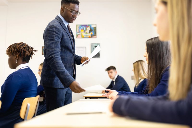 Teacher Distributing Papers to Students in a Classroom