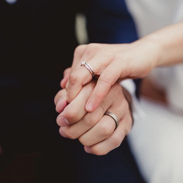 Close-up of a couple holding hands with wedding rings.