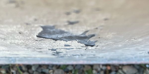 Peeling paint on a surface over rocks.