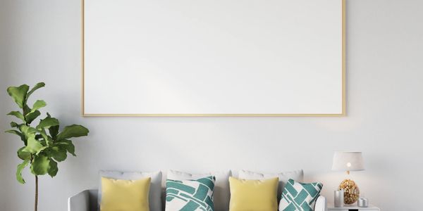 Modern living room with gray sofa, colorful cushions, and blank wall art.