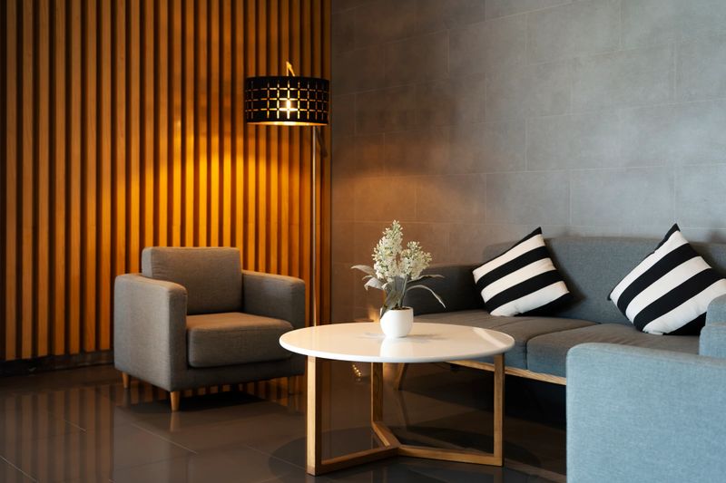 Modern living room interior featuring a luxury wooden wall  white table and fabric arm chairs with stylish furniture decor in warm home house design