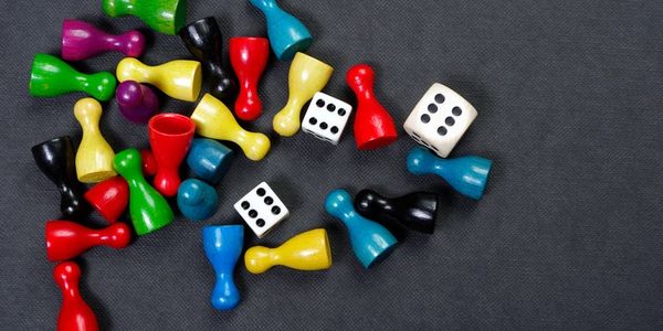 Colorful game pieces and dice scattered on black surface.