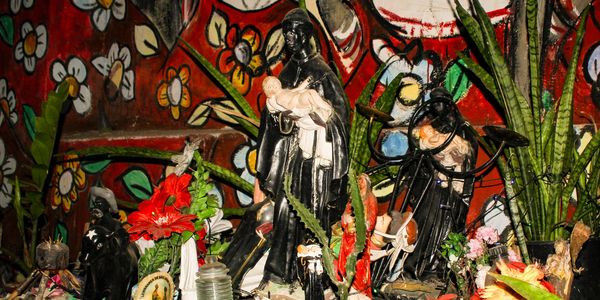 Religious statues surrounded by flowers and plants.