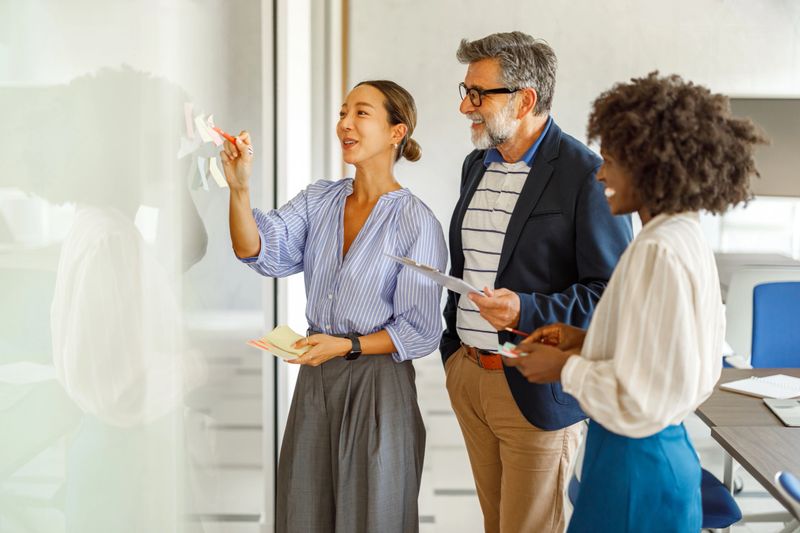 Confident businesswoman explaining innovative ideas to colleagues over sticky notes in office meeting