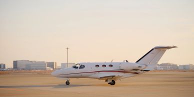 A small private jet on the runway at sunset.