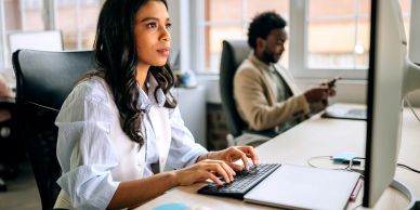Woman focused on typing at computer in office.