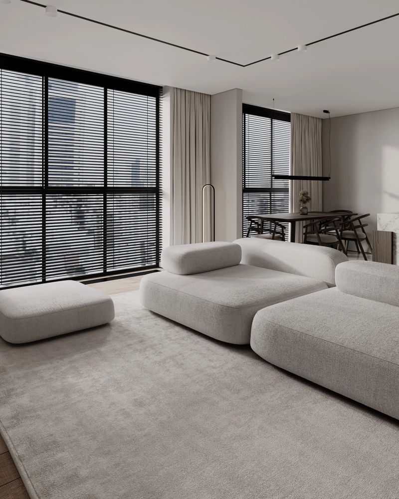 Modern minimalist interior design featuring a spacious living room combined with an open-plan kitchen and dining area. Soft neutral beige and warm wood tones create a calm and elegant atmosphere. Contemporary furniture, clean architectural lines, large windows with natural daylight, and subtle lighting emphasize simplicity, functionality, and comfort. Perfect concept for modern apartment living, Scandinavian and Japandi interior style, luxury real estate, and contemporary home design inspiration.