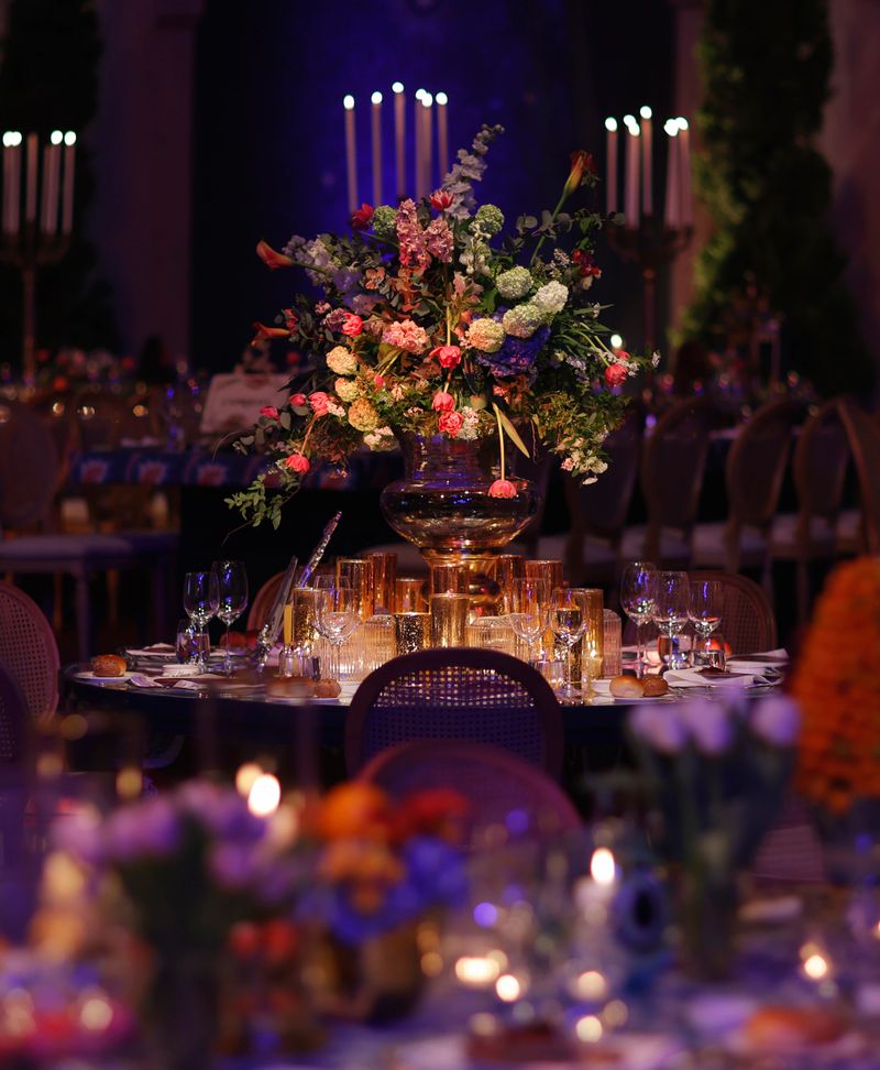 Elegant festive dinner table setting featuring glowing candlelight, fresh pink tulips, rich fruit centerpieces, crystal glassware, and patterned table linens. The warm lighting and vibrant colors create an intimate and luxurious atmosphere, ideal for concepts of fine dining, celebration, cultural events, hospitality, and sophisticated gatherings. stock photo
