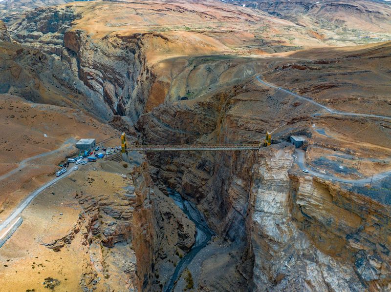 Steel bridge connecting isolated mountain routes across a river gorge in Himachal Pradesh, India.