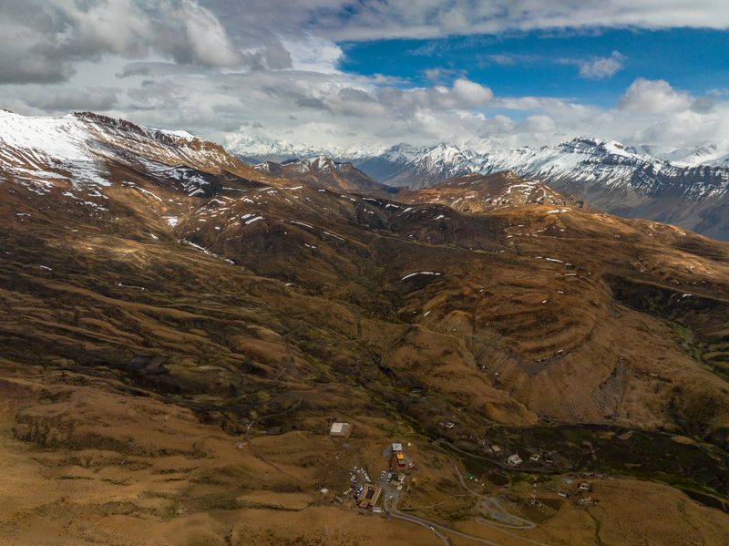 Wide aerial composition capturing the isolation and scale of barren Himalayan ridgelines.