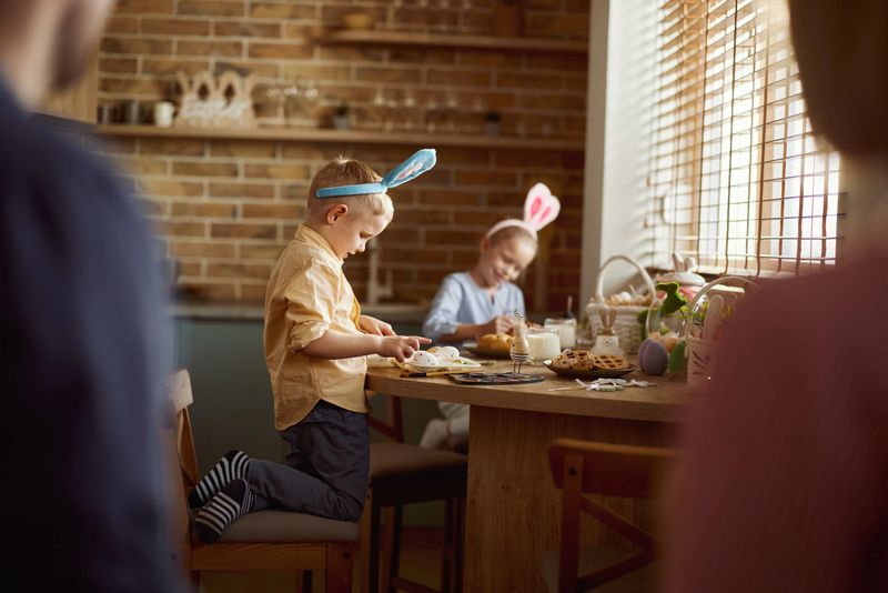 Happy little siblings having fun while painting eggs during Easter at home. Focus is on boy.