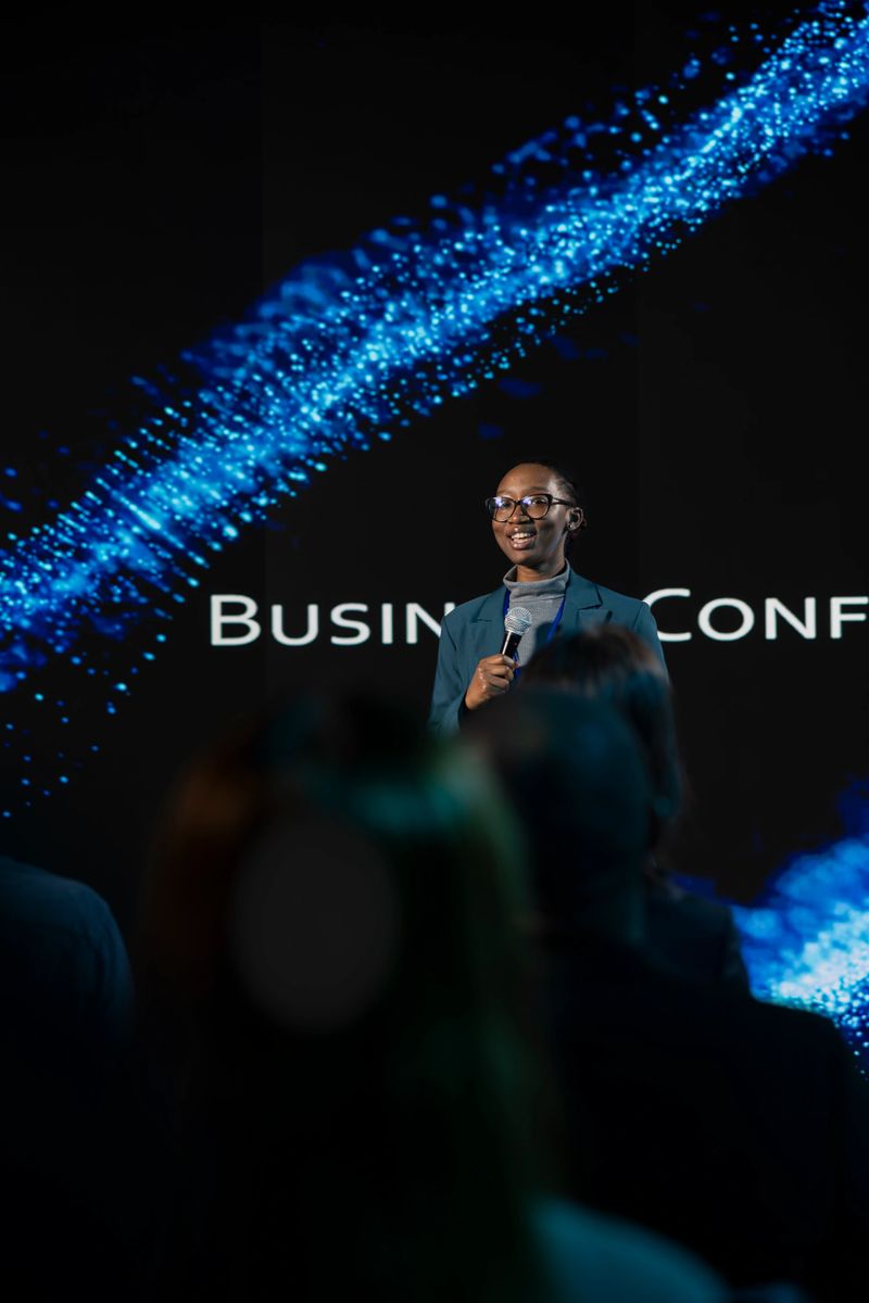 Business forum pitch held by black woman on stage at conference, interacting with listeners and discussing about entrepreneurship tactics for development. International summit.