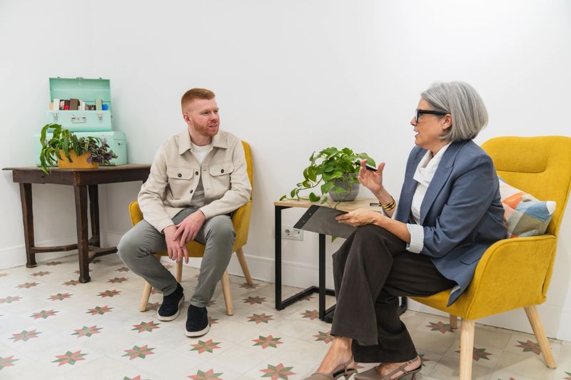 Two adults in smart-casual attire sit in a bright coworking office, engaged in a focused career consultation and discussion