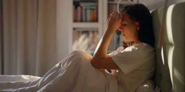 Woman sitting in bed stressed and tired.