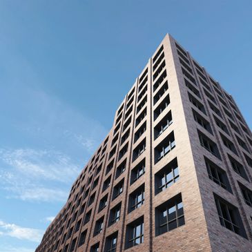 Modern brick building with many windows under a clear blue sky.