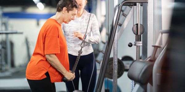 Man lifting weights with trainer guidance.