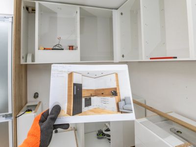 Hand holding kitchen design plan inside an unfinished kitchen.