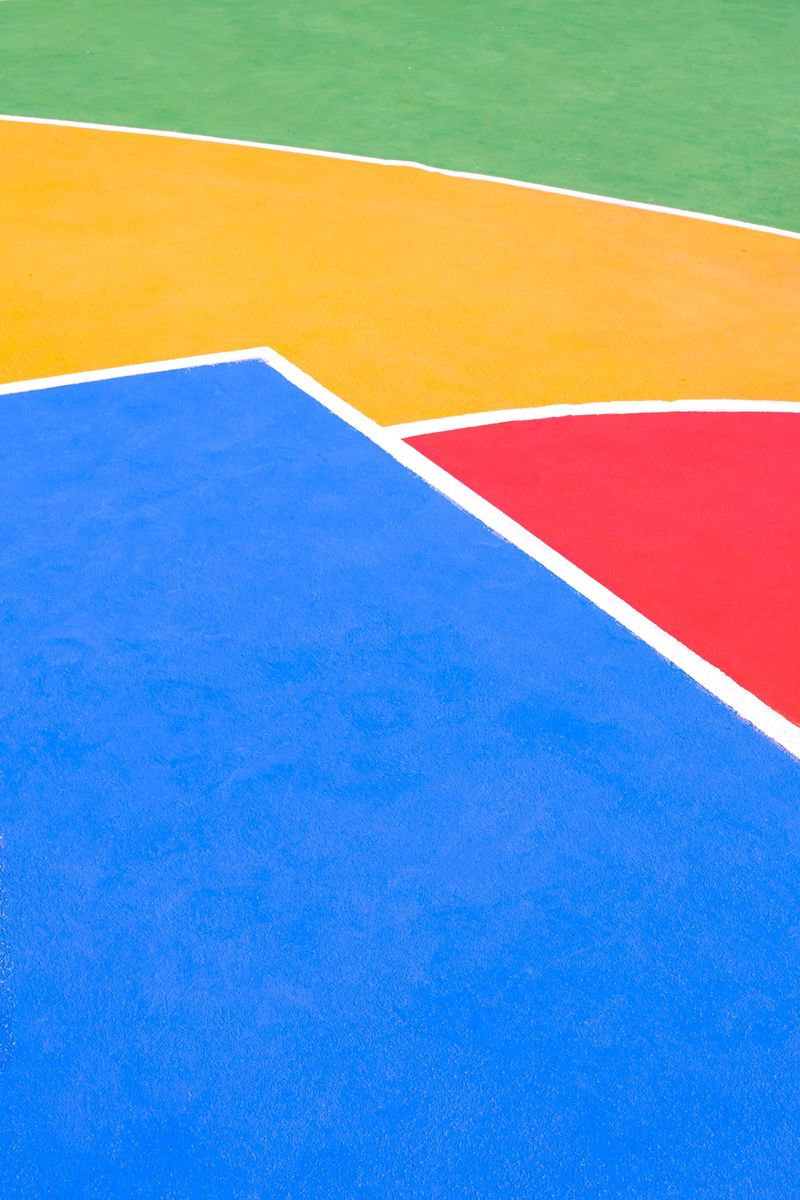 Colorful outdoor basketball court surface with geometric lines. High angle view of vibrant colors painted floor. Minimalist sports vertical background
