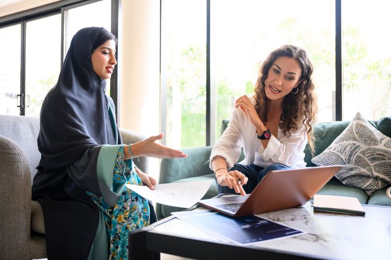 Diverse business professionals collaborating on a laptop, discussing new strategies and sharing ideas in a modern office, highlighting teamwork and mentorship
