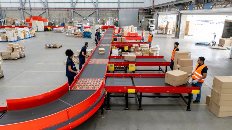 Aerial view of a group of Latin American employees sorting boxes of merchandise on a conveyor belt at a distribution warehouse