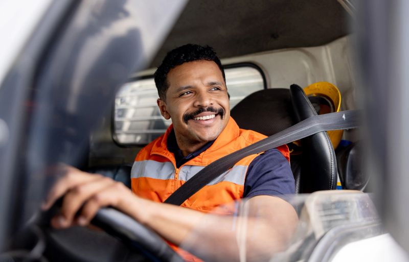 Happy Latin American truck driver delivering packages and smiling - freight transportation concepts