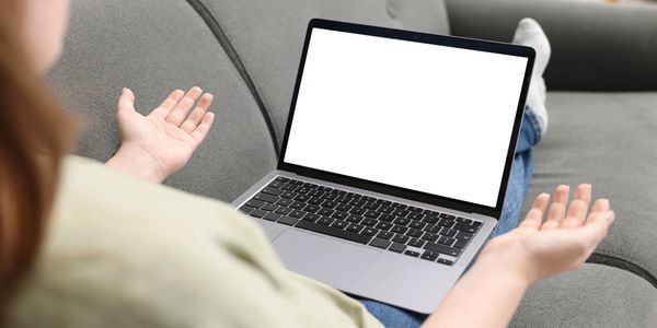 Person confused over blank laptop screen on couch.