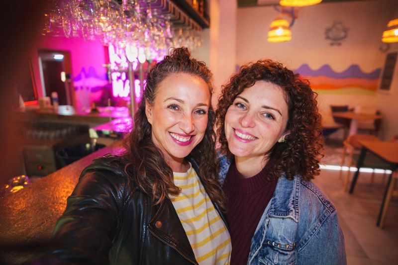 Happy young adult women enjoying nightlife taking selfie