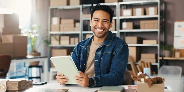 Small business owner smiling in a warehouse, managing import/export inventory.