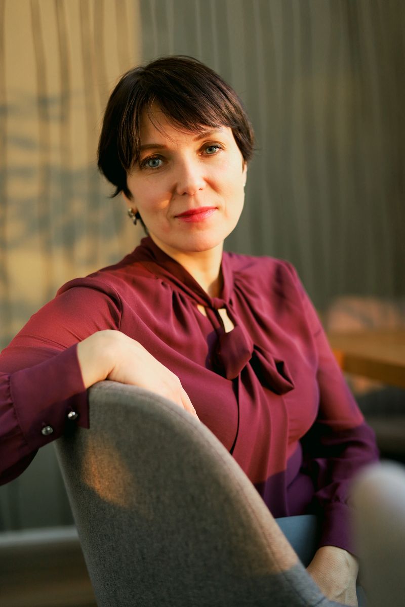 A confident woman sits in warm natural light, creating a calm and professional portrait ideal for business, coaching, consulting, corporate identity, and personal branding projects.