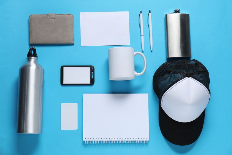 Different blank items for branding on light blue background, flat lay. Mockup for design
