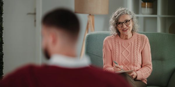Terapeuta hablando con paciente en consultorio.