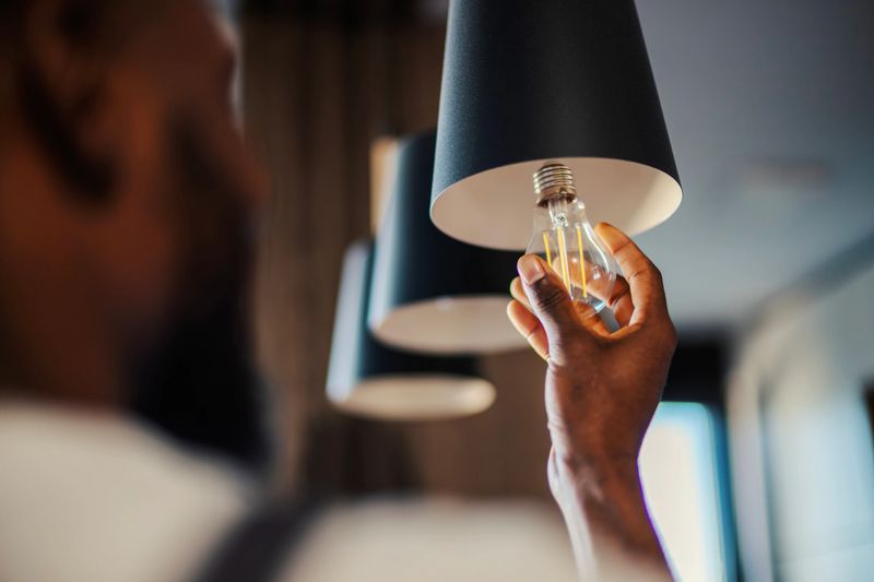 Adult handyman replacing an energy-efficient led light bulb into a metal ceiling fixture, focusing on home improvement, maintenance, and sustainable lifestyle